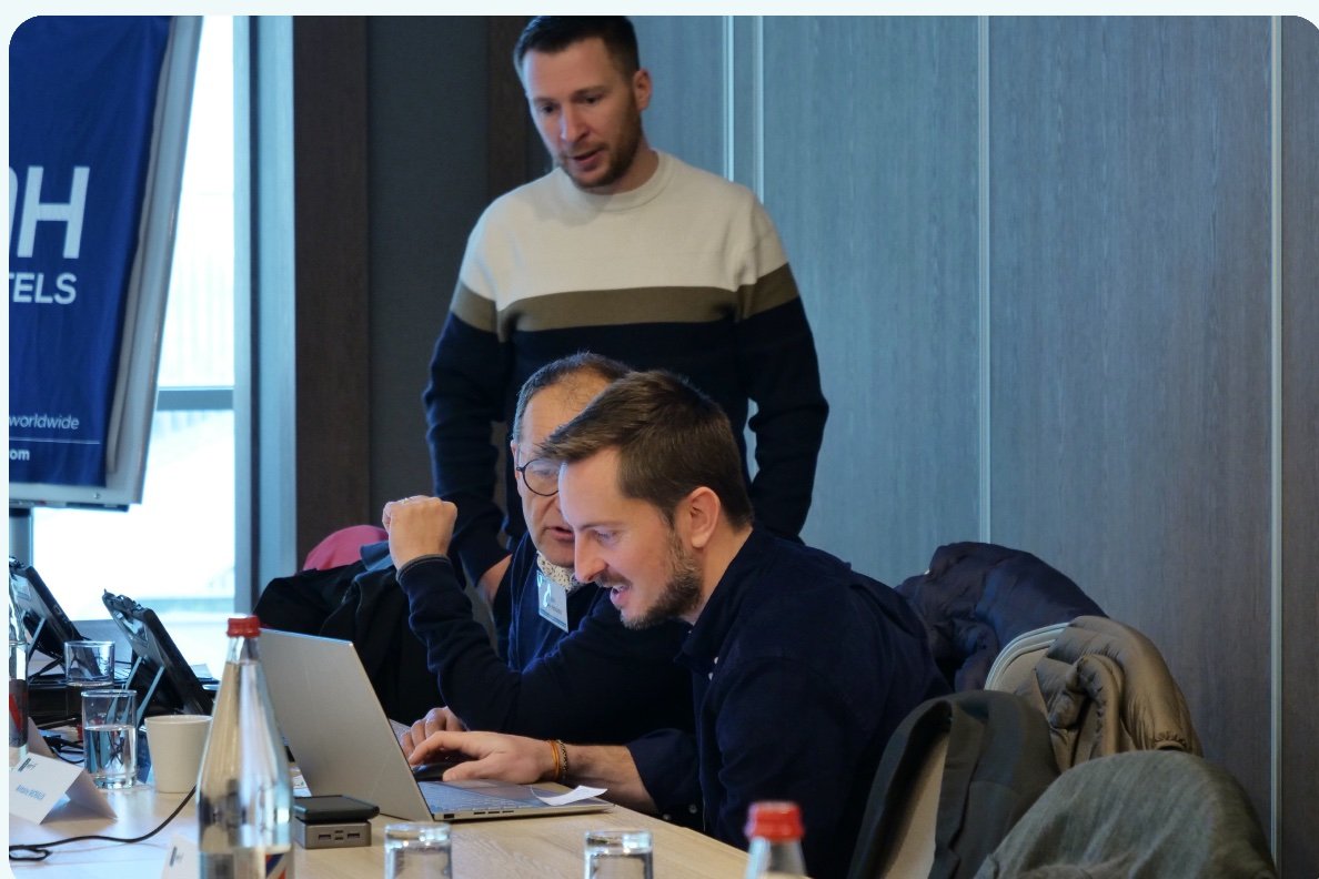 Un formateur accompagne des participants devant leurs ordinateurs
