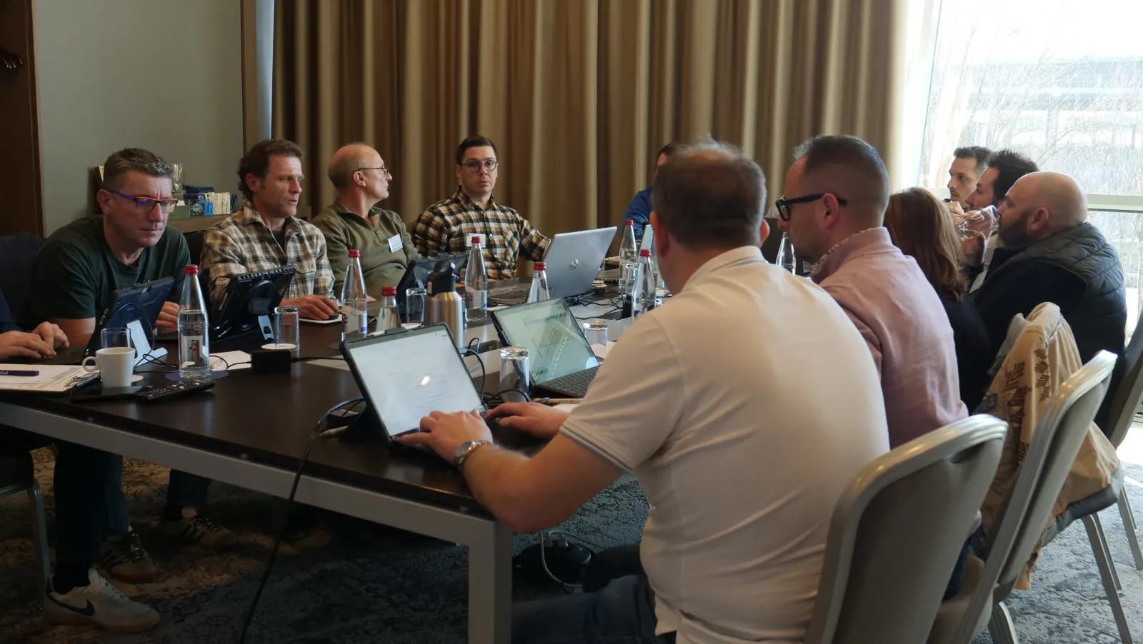 Stagiaires réunis autour d'une table de réunion, ordinateurs ouverts, pendant une session de formation Ivérif